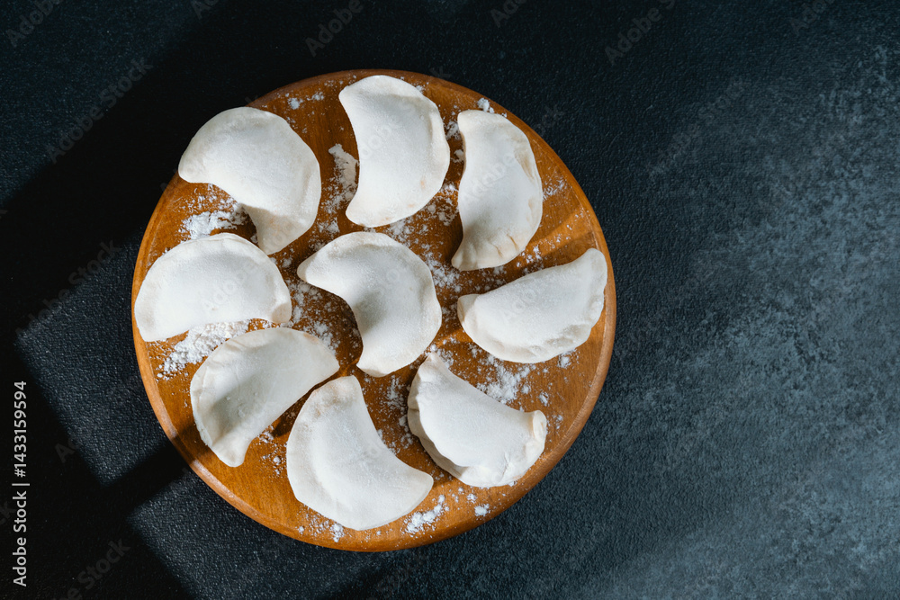 Freshly prepared dumplings arranged on a wooden platter in a kitchen