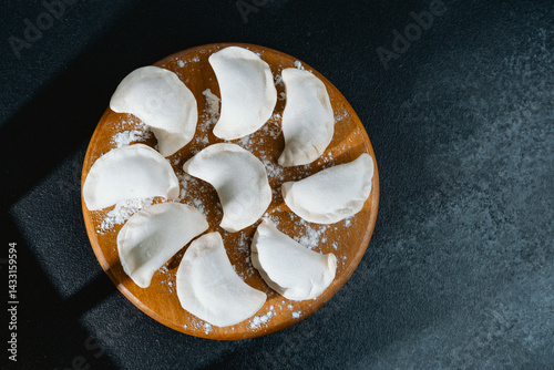 Obraz na płótnie Freshly prepared dumplings arranged on a wooden platter in a kitchen w salonie