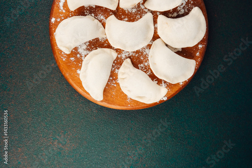 Obraz na płótnie Handmade dumplings arranged on a wooden board ready for cooking w salonie