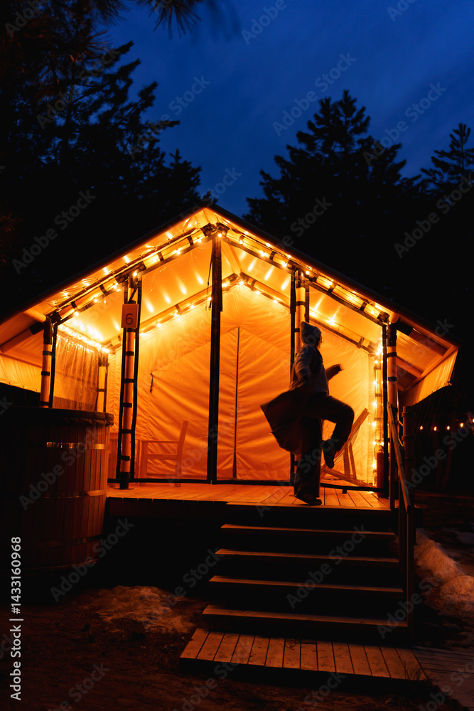 Glamping from tent houses in the forest in the dark. silhouette of a woman