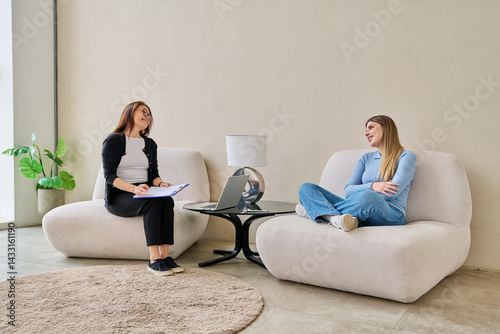 Obraz na płótnie Young smiling woman in mental therapy talking with professional psychologist w salonie
