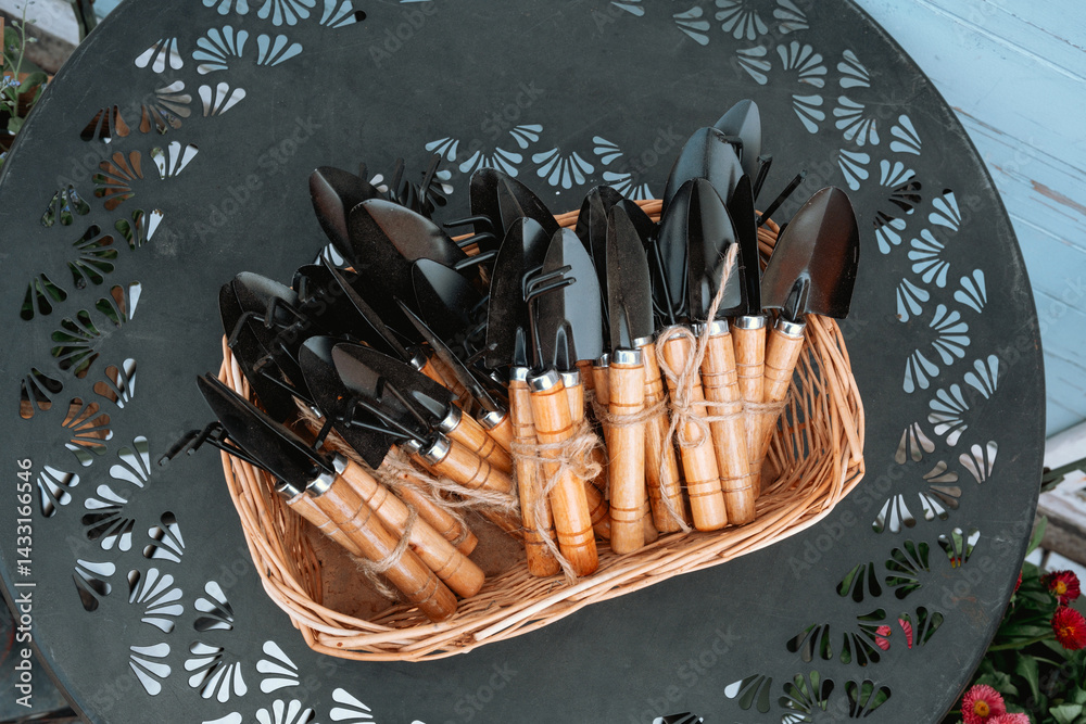 Garden tools arranged in a wicker basket on a decorative metal table outdoors