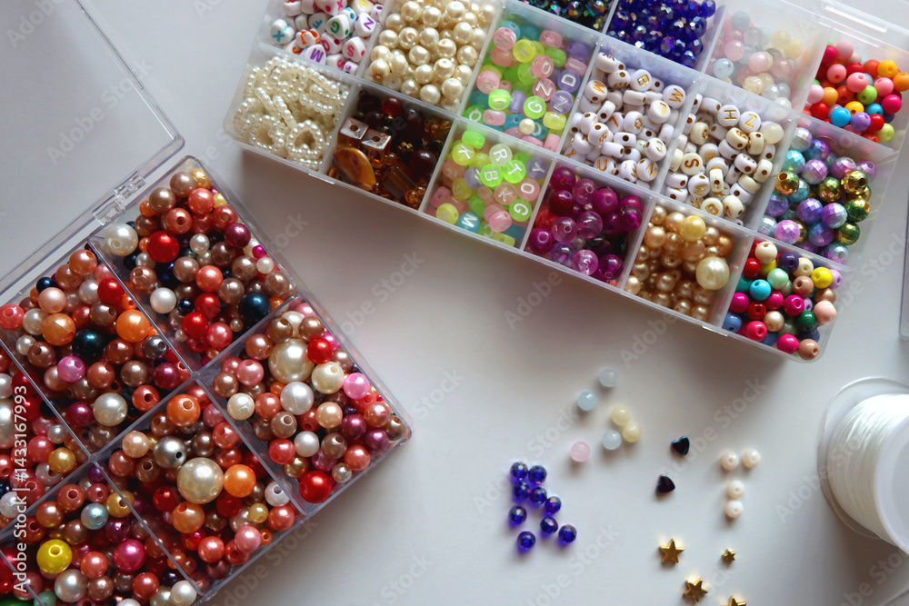 Hand figurine, colorful friendship bracelets, necklaces, various beads and DIY supplies on the table. Making jewelry at home. Flat lay.