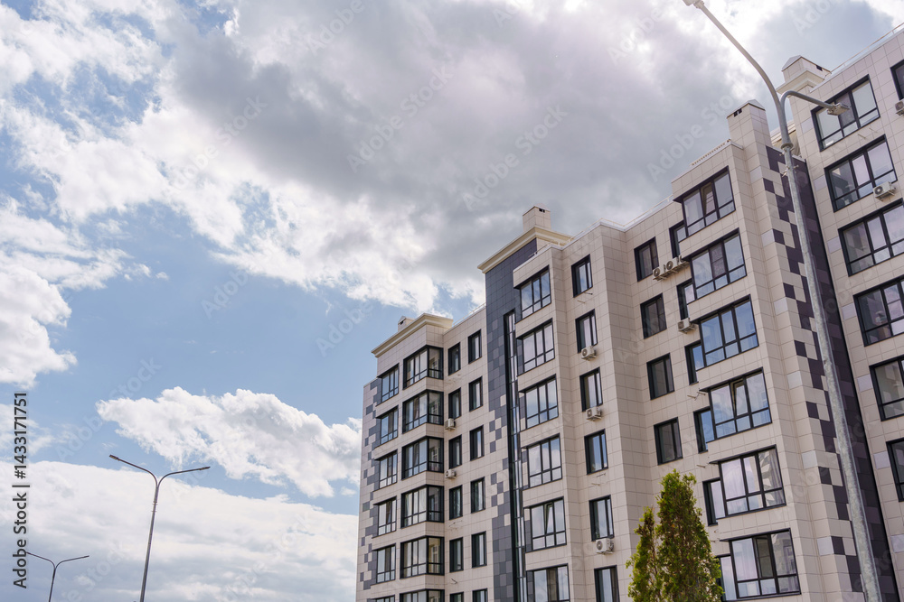 A multi-storey modern building against the background of the sky with clouds.