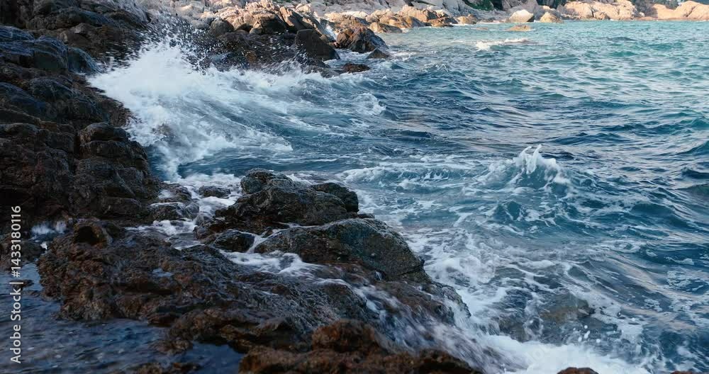 Ocean waves crash against stones along a rocky shoreline in a serene coastal setting Ocean waves crash against stones along a rocky shoreline in a serene coastal setting