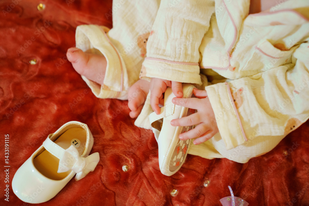The little girl is holding small white shoes with bows in her hands.