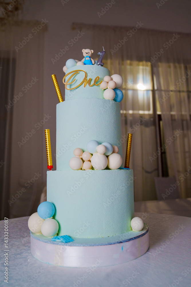 a blue three-tiered cake decorated with bear cub and caramel balls