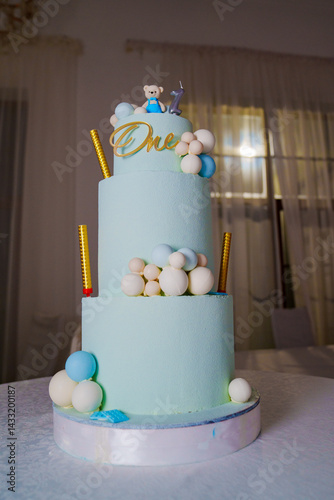 a blue three-tiered cake decorated with bear cub and caramel balls