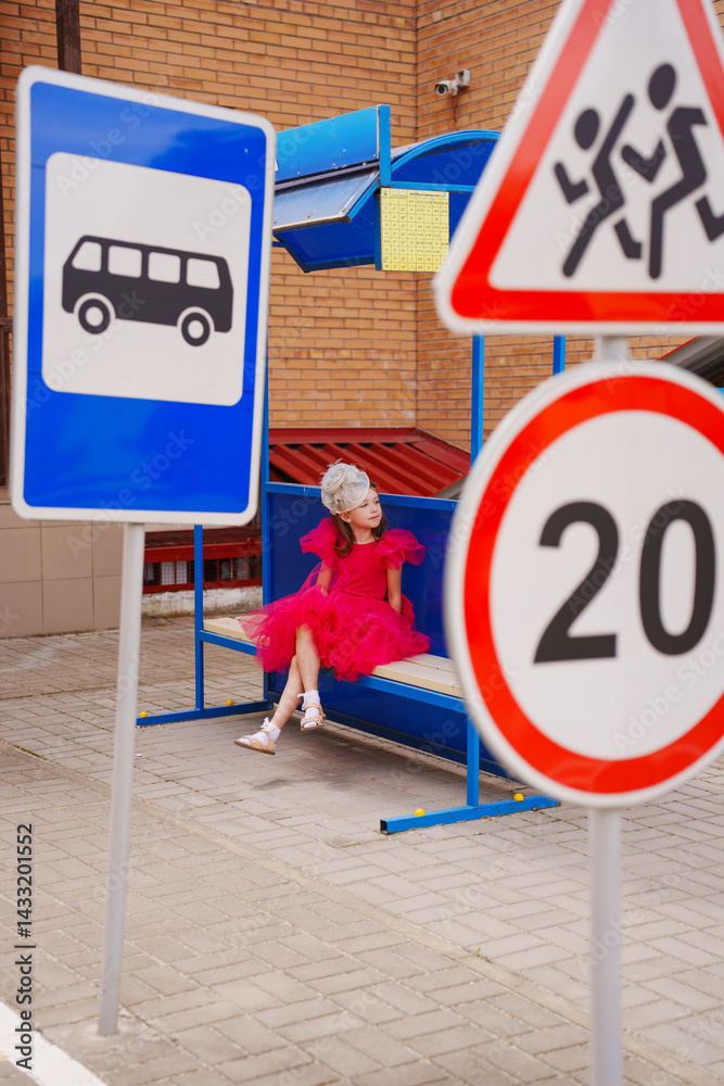 A girl in a lush pink dress on the playground to learn the rules of the road