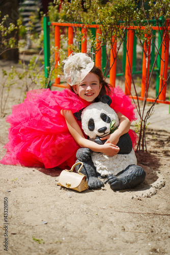 A girl in an lush pink dress is playing on the playground with animal sculptures