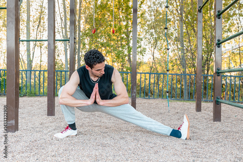 Man performing Cossack squat stretch in outdoor calisthenics park for hip mobility, balance, and leg flexibility, wearing fitness apparel on gravel surface
