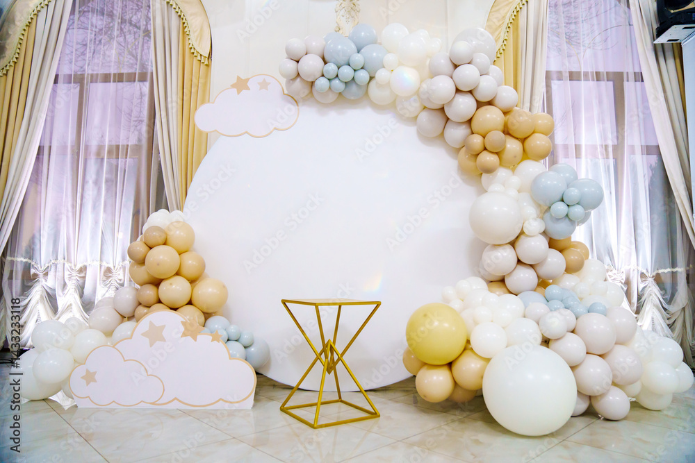 Round white background decorated with balloons and cake table.