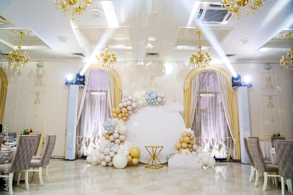 Round white decorated with balloons and cake table in the banquet hall.