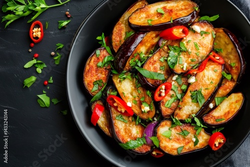 Obraz na płótnie Fried eggplant slices with chili pepper and fresh herbs in black bowl w salonie