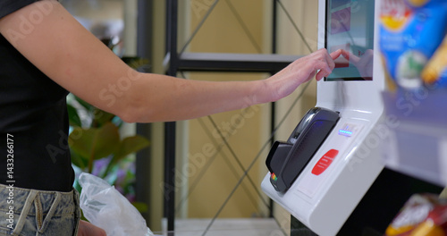 Customer pays at self-checkout using smartphone next to grocery bag photo