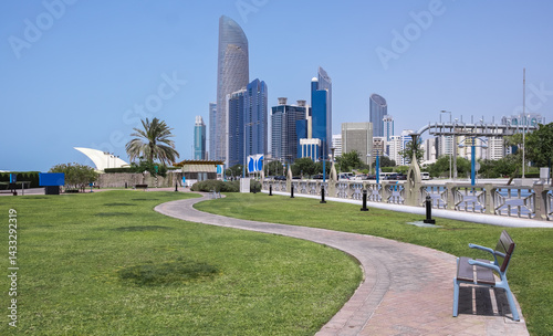 Corniche promenade in Abu Dhabi, UAE. Beautiful walkway in urban city park with green trees