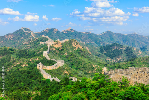 The great wall of china winds through lush green mountains under blue sky