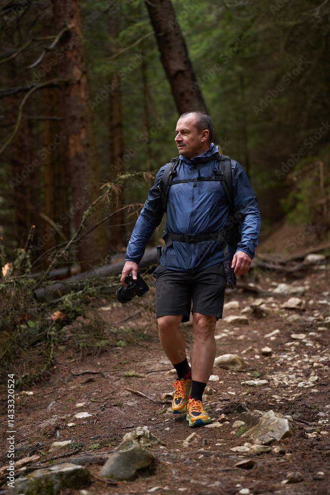 Photographer hiking uphill through forest trail