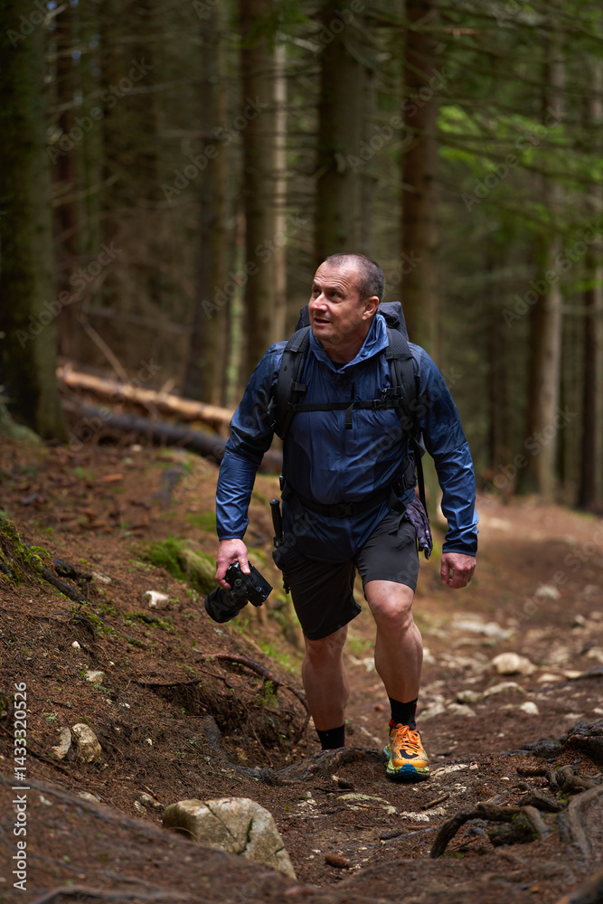 Photographer hiking uphill through forest trail