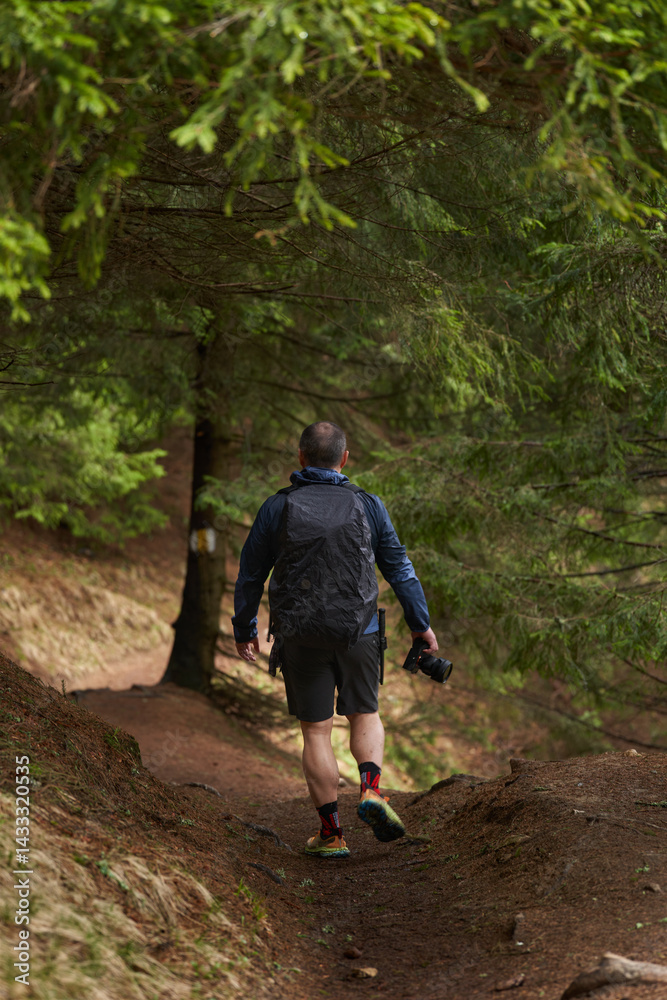 Man descending a forest trail in hiking gear