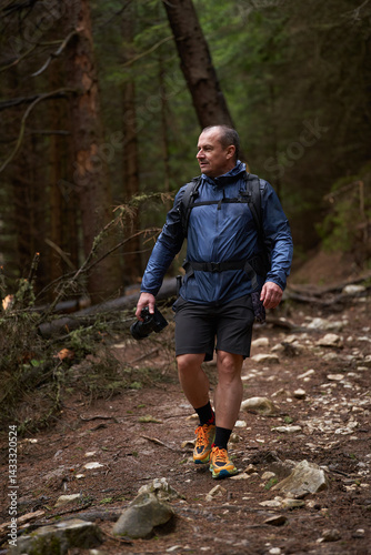 Obraz na płótnie Photographer hiking uphill through forest trail w salonie