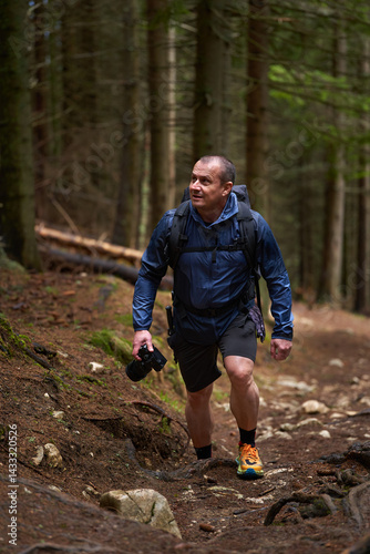 Obraz na płótnie Photographer hiking uphill through forest trail w salonie