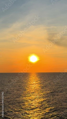 Vertical video of a sunset on the beach in The Hague, Netherlands. Wind turbines silhouette the horizon. A bird flies across the sky. A stunning moment of peace and beauty on the coast. 