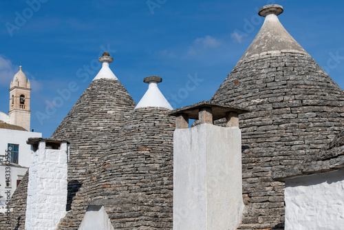 Close up of characteristic conical stone roofs of Trulli houses in the city of Albarobello, Puglia, Italy with blue sky as background