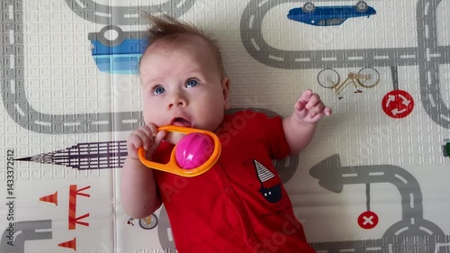 Four-month-old baby girl playfully plays with a rattle
