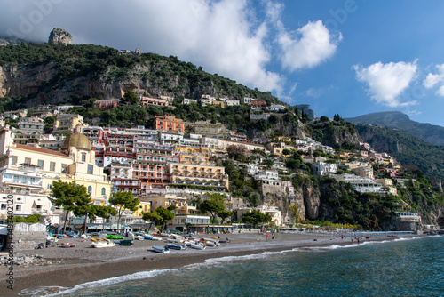 Fototapeta Naklejka Na Ścianę i Meble -  Positano, Italy-5 November 2024; Panoramic view over the beach with sun chairs and beach umbrellas along the Amalfi Coast (Province of Salerno) with steep hill buildings in background