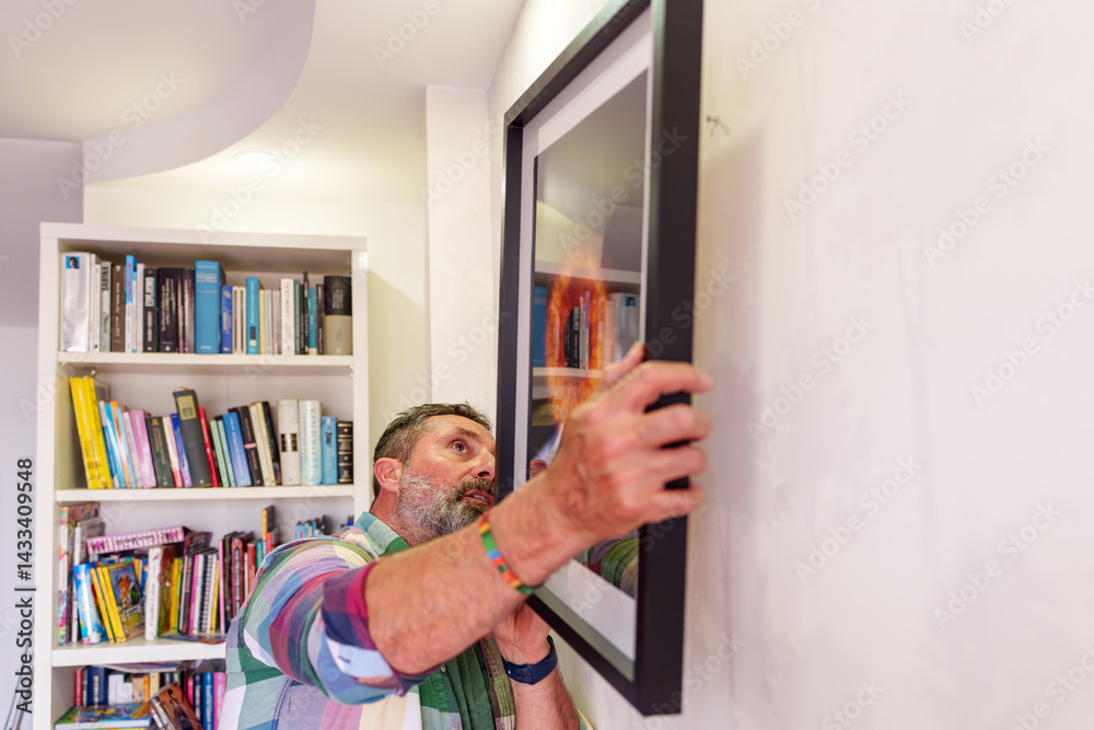 Fototapeta premium Interior designer hanging a framed painting of a solar eclipse on a white wall in a modern living room