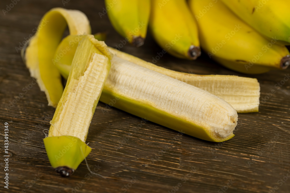 open bananas on the table, a bunch of bananas on a board one of which is open, close-up