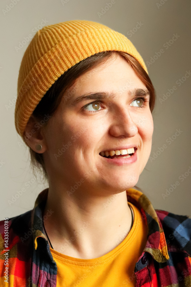 Smiling young hipster woman in her 20s or 30s wearing a trendy hat and yellow outfit, close-up portrait with cheerful expression and stylish vibe