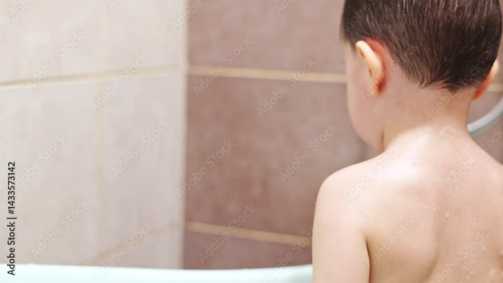 kid is taking shower, singing and having fun. boy washing head, hair with shampoo, water drops falling from top on child face.mother help preschooler holding spray hand shower. kid is taking shower, singing and having fun. boy washing head, hair with shampoo, water drops falling from top on child face.mother help preschooler holding spray hand shower.