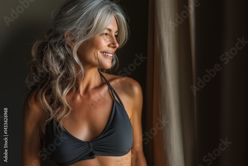 Mature woman with loose skin and fat, wearing black bikini top, smiling. Concept of confidence and warmth embracing loose skin and fat, highlighting weight loss journey.