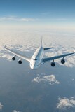 Passenger airplane flying above clouds in clear blue sky