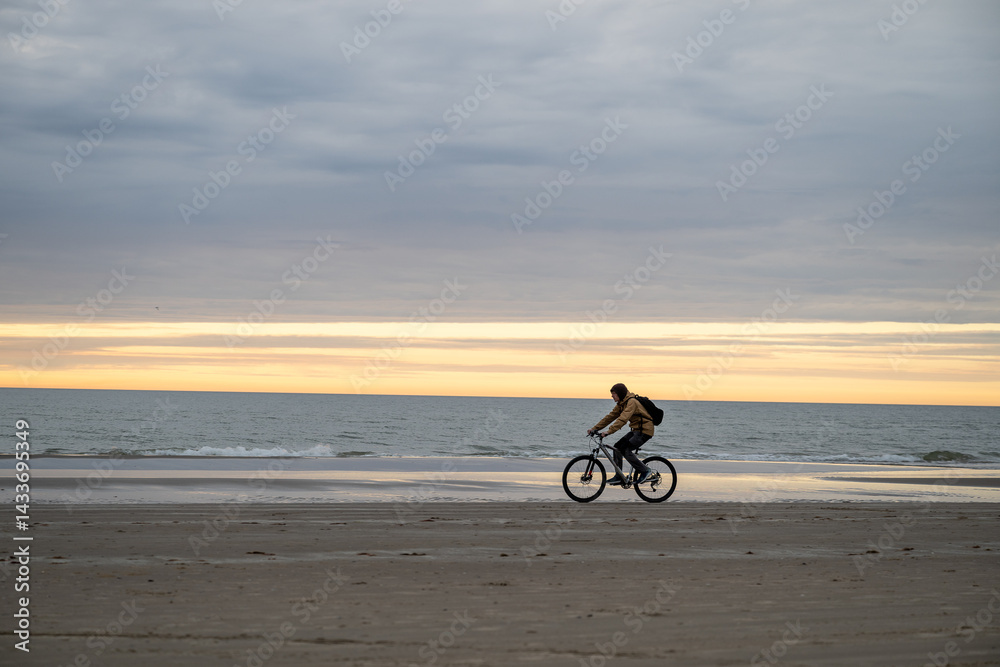 Fototapeta premium man riding bicycle on North sea coast in Denmark
