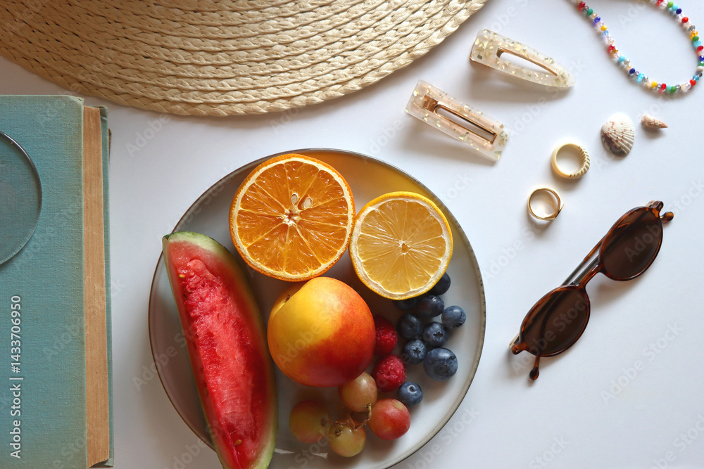 Glass of cocktail, straw hat, sunglasses, books, fresh fruit, chocolate and accessories. Summer essentials on the table. Top view.