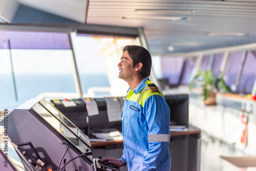 Chief officer on the bridge of a merchant ship, wearing a light blue uniform with epaulettes, working with pride and confidence - an authentic portrait of leadership at sea. Real workplace. Chief officer on the bridge of a merchant ship, wearing a light blue uniform with epaulettes, working with pride and confidence - an authentic portrait of leadership at sea. Real workplace.