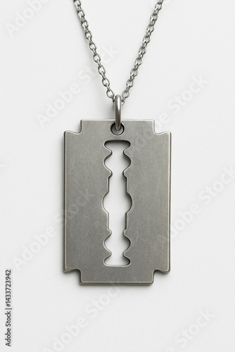 A close-up of a metal razor blade pendant hanging from a thin silver chain, with a small vent (cutout design) in the center, photographed against a clean white background