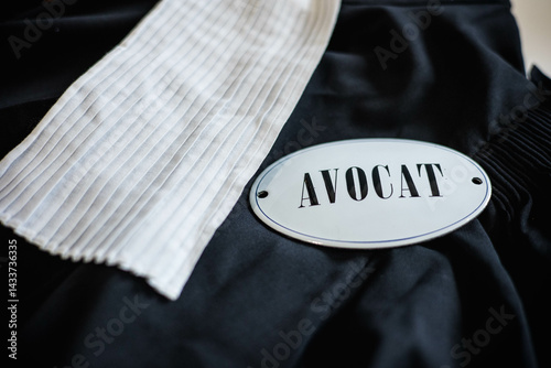 Une robe d'avocat noir posée sur une table avec dessus, une carte qui indique avocat