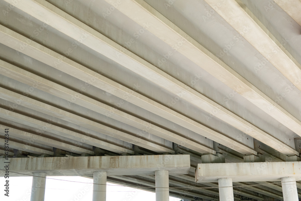 Obraz premium Abstract industrial photo with bottom view of a road bridge with concrete pillars.