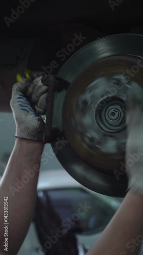 A car mechanic repairs the brake system of an old car.