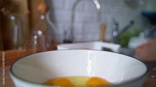 Woman cracking eggs into a cup in the kitchen. Healthy food made from plant ingredients. Cooking scrambled eggs.