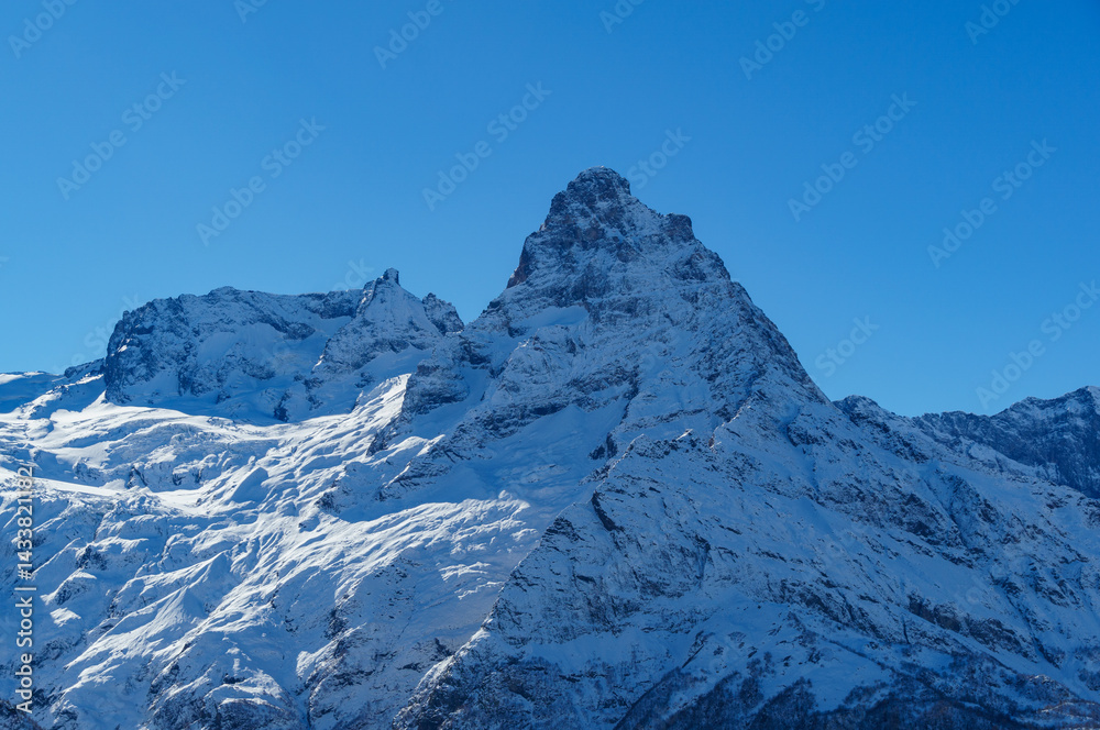 Obraz premium Picturesque landscape in Dombay with amazing snow-capped peaks and majestic blue slopes of North Caucasus Mountains. Mountain ski resort in Karachay-Cherkessia, Russia