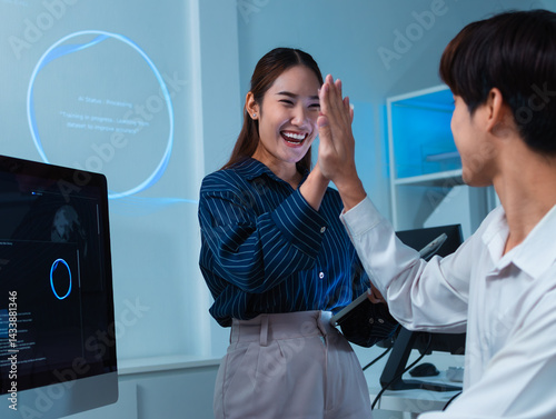Celebrating success project, Cheerful Two Asian software developer, programmer celebrate development software project, result in office. Asian Programmers colleagues giving high five to each other.
