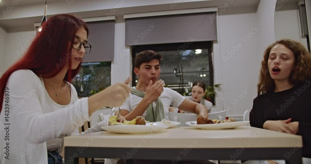 Friends enjoying a meal together at a table, talking and laughing. Students having breakfast or lunch during break at school. Happy diverse young people enjoying their time together.