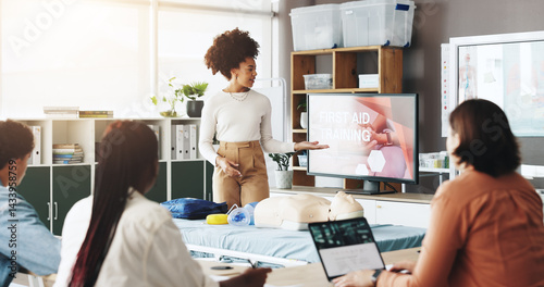 Woman, paramedic or presentation with screen for first aid training, emergency service or health and safety. Female person, teacher or students with display for medical course or rescue demonstration