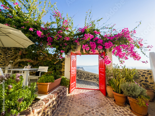Obraz na płótnie Santorini island, Greece. Beautiful patio with red door and blooming pink flowers at sunset w salonie