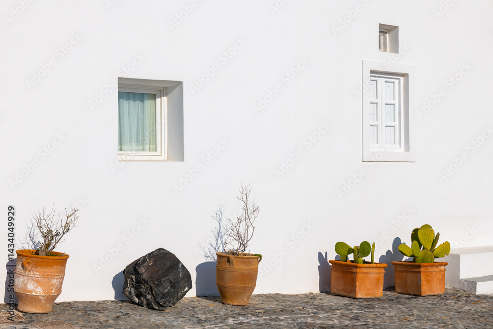 White cycladic architecture in Santorini island, Greece. Ceramic pots with plants on the street